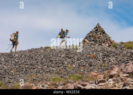 Thru-Wanderer nähert sich eine perfekte Cairn entlang des Pacific Crest Trail unter alten Verschneiten in die Ziege Felsen, Wüste, Gifford Pinchot National Forest, W Stockfoto