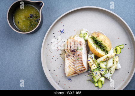 Moderne Deutsche Frittierter Kabeljau Filet mit weißen Spargelspitzen und Bratkartoffeln als Draufsicht auf einer Platte Stockfoto