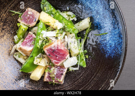 Moderne gebratener Thunfisch tataki Rinderfilet Salat mit weißen Spargel Zucker Snaps und Parmesan als Draufsicht auf einer Platte Stockfoto