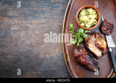 Traditionelle bayerische Schweinshaxe mit Kartoffelsalat als Draufsicht auf einer Platte Stockfoto