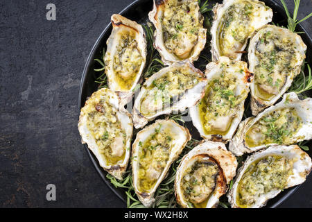 Grill overbaked frische Austern mit Knoblauch und Kräuter als Draufsicht auf einem Tablett mit Kopie Raum angeboten geöffnet Links Stockfoto