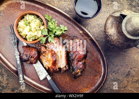 Traditionelle bayerische Schweinshaxe mit Kartoffelsalat als Draufsicht auf einer Platte Stockfoto