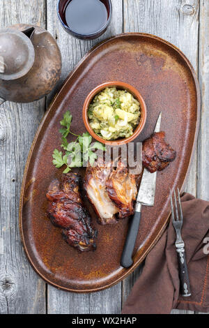 Traditionelle bayerische Schweinshaxe mit Kartoffelsalat als Draufsicht auf einer Platte Stockfoto