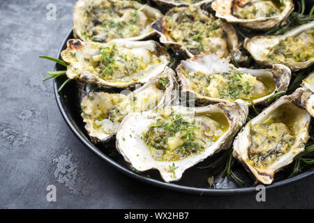 Grill overbaked frische Austern mit Knoblauch und Kräuter als Draufsicht auf einer Platte angeboten geöffnet Stockfoto