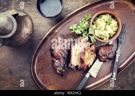 Traditionelle bayerische Schweinshaxe mit Kartoffelsalat als Draufsicht auf einer Platte Stockfoto