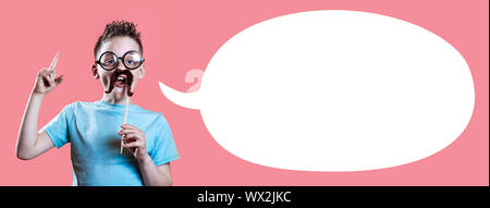 Ein Junge in einem hellen t-shirt mit einem Schnurrbart und Gläser hält seinen Zeigefinger gegen einen hellen Hintergrund Stockfoto