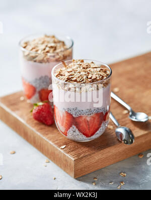 Hausgemachte Hafer Müsli mit Erdbeeren und in Gläsern mit Scheiben von Erdbeeren, Chia Samen auf Holz- Hintergrund. Kopieren Sie Platz. Stockfoto