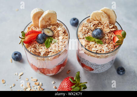 Diätetische natürliche Frühstück mit natürlichen organischen Inhaltsstoffe - Erdbeeren, Müsli, Banane in einem Glas auf einen hölzernen Tisch. Gesund Stockfoto
