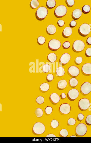 Feder organische gesundes Gemüse - Scheiben von rettich in einer kreativen Muster auf einem gelben Hintergrund. Flach. Stockfoto