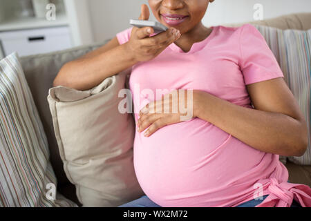 Schwangere Frau mit Voice-Recorder auf smartphone Stockfoto