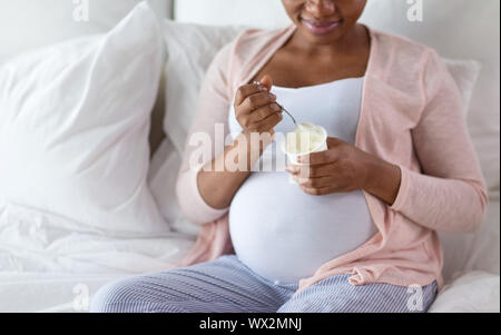 Schwangere Frau isst Joghurt zum Frühstück im Bett Stockfoto