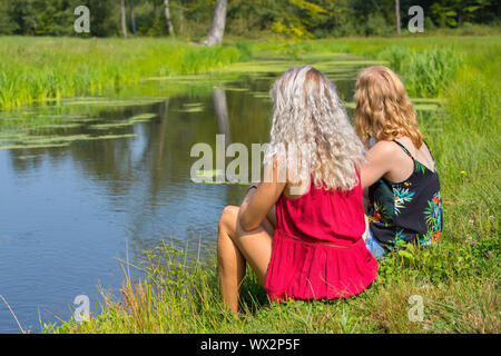 Zwei junge Frauen sitzen zusammen im Waterfront Stockfoto