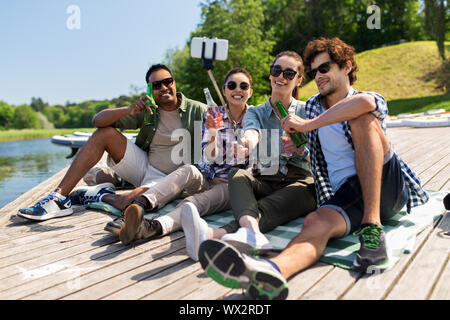Freunde mit Getränken unter selfie auf See Pier Stockfoto