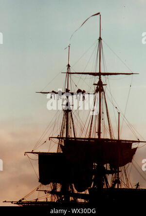 Eine silhouette Foto von Matrosen arbeiten an der Takelage eines modernen Segelschiff (Abschleppen/Senken der Segel) in der Dämmerung während des Besuchs des Bemühen, Whitby, Yorkshire, England im Jahr 2000. Stockfoto