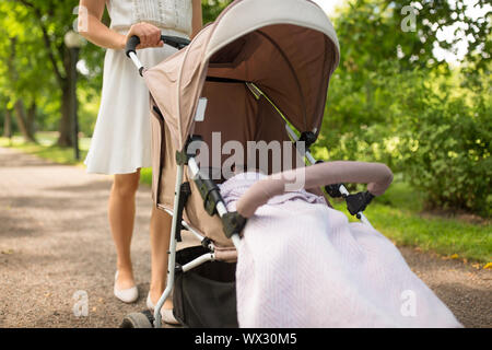 Mutter mit Kind im Kinderwagen spazieren im Park Stockfoto