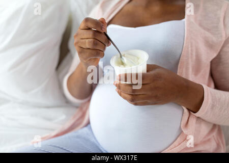 Schwangere Frau isst Joghurt zum Frühstück im Bett Stockfoto