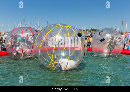 Kinder haben Spaß im Inneren von Ballons auf dem Wasser während der Fahrt Stockfoto