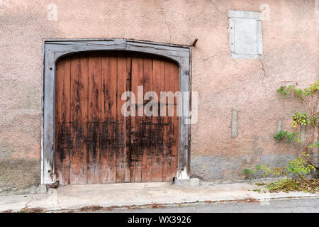 Große Oldtimer Garage Tür oder Tor in einem historischen rosa Haus vorne mit einem grünen Weinpflanze auf t Stockfoto