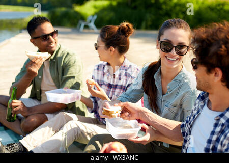 Gerne Freunde mit Picknick am See Pier im Sommer Stockfoto