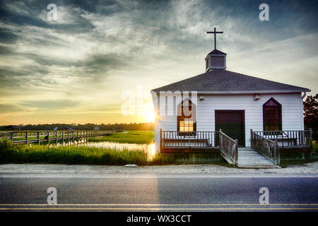 Kleine weiße hölzerne Kapelle auf dem Wasser an der Küste, während ein bunter Sommer Sonnenuntergang Stockfoto