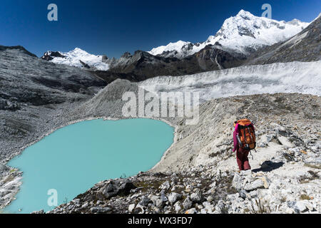 Weibliche Bergsteiger passiert einen türkisfarbenen See in den Anden in Peru Stockfoto