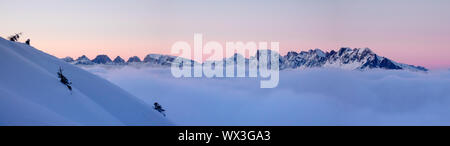 Winter Berge bei Sonnenuntergang mit Schnee und Wolken im Vordergrund. Stockfoto