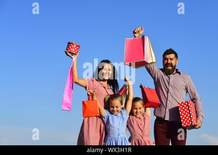 Mann, Frau und Kinder mit Geschenken auf Himmel Hintergrund. Mutter, Vater und Kinder mit Taschen und Rucksäcke. Familie mit lächelnden Gesichtern offen präsentiert ou Stockfoto