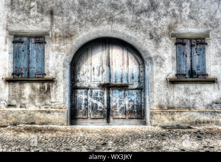 Detaillierte Ansicht des alten rustikalen Vintage House front mit blass blauen Tor und Fensterläden Stockfoto