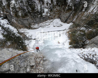 Ice climber Abseilen aus einem steilen Eisfall in den italienischen Alpen Stockfoto