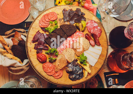 Italienische Antipasti Wein Snacks. Brushettas, Käse, mediterrane Oliven, Gurken, Prosciutto di Parma mit Melone, Salami und Wein im Glas Stockfoto