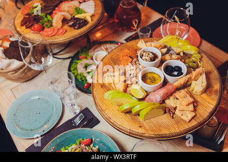 Italienische Antipasti Wein Snacks. Brushettas, Käse, mediterrane Oliven, Gurken, Prosciutto di Parma mit Melone, Salami und Wein im Glas Stockfoto