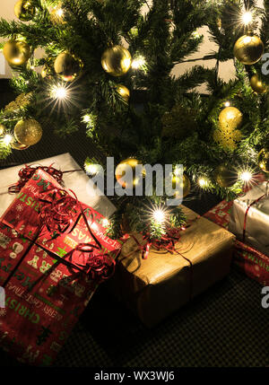 Bunte Geschenke unter einem schön geschmückten Weihnachtsbaum mit Kugeln und Lichtern Stockfoto