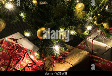 Bunte Geschenke unter einem schön geschmückten Weihnachtsbaum mit Kugeln und Lichtern Stockfoto