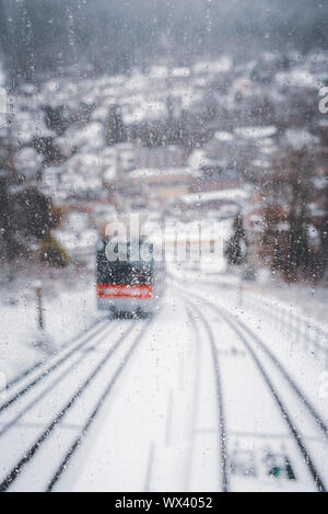 Eisenbahn Seilbahn Klettern in verschneiten Titel, durch das Fenster gesehen. Defokussierten Bild. Winter Spaß. Landschaft in Bad Wildbad, Deutschland. Schlechtes Winterwetter. Stockfoto