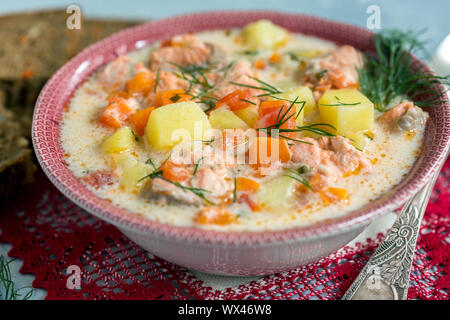 Cremige Suppe mit Lachs, Gemüse und frischem Dill in eine Schüssel geben. Stockfoto