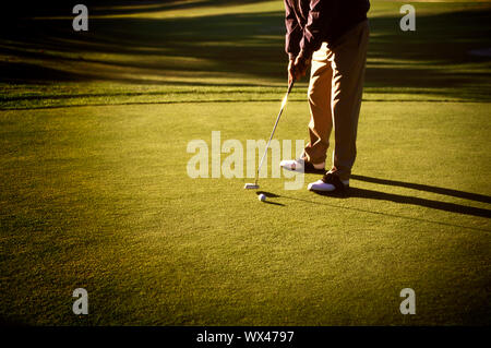 Ein Mann spielt Golf auf dem Putting Green. Stockfoto