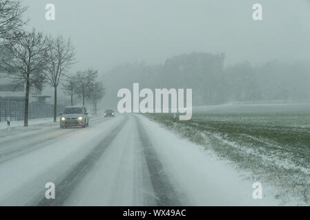 Schneesturm auf der Landstraße und gefährliche Straßenverhältnisse im Winter mit Autos fahren Stockfoto