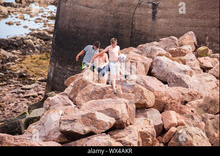 Kinder spielen auf den Felsen am Victoria Harbour. Dunbar ist eine Stadt im Südosten von Schottland. Stockfoto