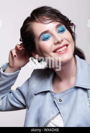Portrait von lächelnden Frau in der blauen Jacke. Frau mit außergewöhnlicher Schönheit Make-up und das nasse Haar und blauen Schatten Make-up. Stockfoto