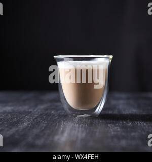 Frisch Cappuccino mit Schaumstoff in ein Glas Schale auf einem schwarzen Holztisch rund um einen dunklen Hintergrund mit Kopie Raum gebraut. Stockfoto