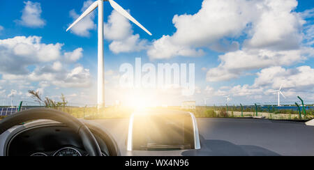 Windenergieanlagen auf Landschaft entlang leere Straße gegen den Himmel Stockfoto