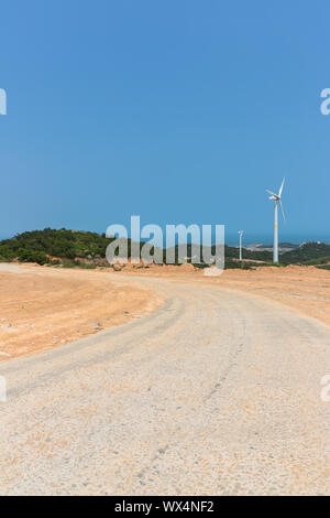 Windenergieanlagen auf Landschaft entlang leere Straße gegen den Himmel Stockfoto