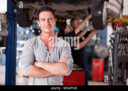 Porträt eines männlichen Mechaniker mit Arbeiter im Hintergrund in die Kamera schaut Stockfoto