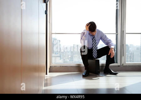 Young Business Mann sitzt in der Depression mit der Hand auf den Kopf Stockfoto