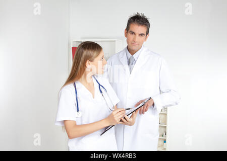 Lächelnd weibliche Arzt mit Zwischenablage in den männlichen Arzt. Stockfoto