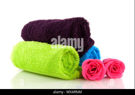 blau grün und Aubergine gefärbt gerollte Handtücher mit Seife Rosen Stockfoto