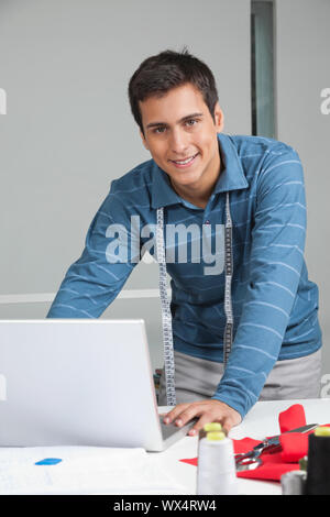 Portrait von jungen männlichen Maßgeschneiderte mit Laptop im Stehen durch die Tabelle Stockfoto