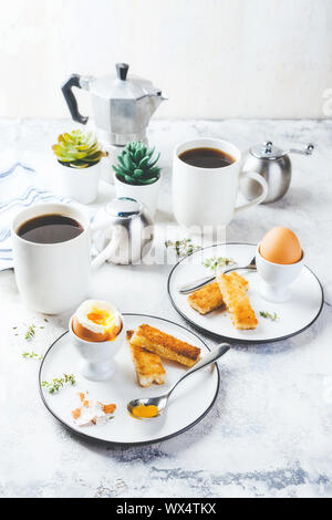 Weich gekochte Eier zum Frühstück mit Toast und Kaffee Tasse im Hintergrund Stockfoto