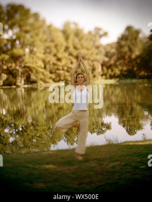 Frau üben von Tai Chi vor einem See. Stockfoto