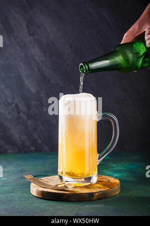 Glas Becher mit Bier mit Schaum und Wasser Tropfen auf einen dunkelgrünen Hintergrund Stockfoto